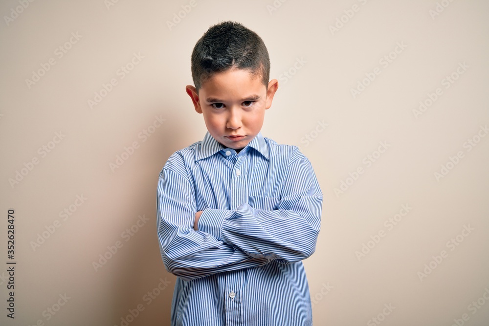 Young little boy kid wearing elegant shirt standing over isolated background skeptic and nervous, disapproving expression on face with crossed arms. Negative person. Young little boy kid wearing elegant shirt standing over isolated background skeptic and nervous, disapproving expression on face with crossed arms. Negative person.