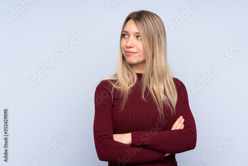 Young blonde woman over isolated blue background portrait