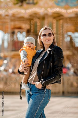 Stylish young mom walks with the baby in the park. Happy Mom