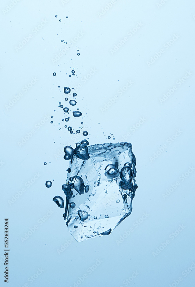 Ice piece falling in the water with bubbles. Cold water, ice cube, ice chunk. Light blue background. High speed photography Ice piece falling in the water with bubbles. Cold water, ice cube, ice chunk. Light blue background. High speed photography