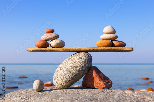 Symbolic scales of the stones against the sea. Pros and cons concept