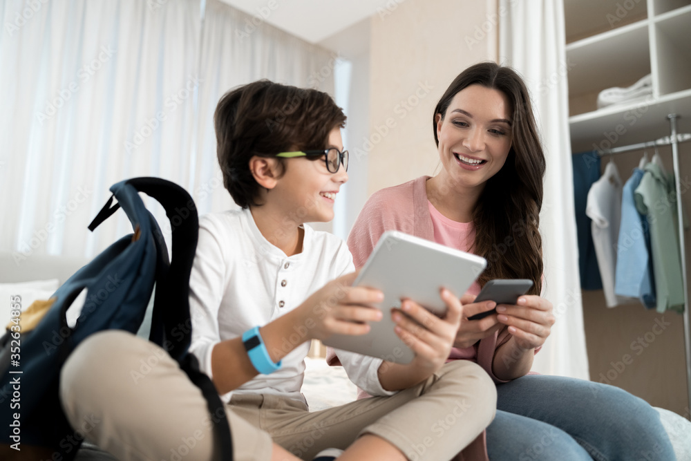 Woman with a smartphone staring at her son tablet