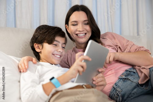 Boy with a gadget sitting next to his mother