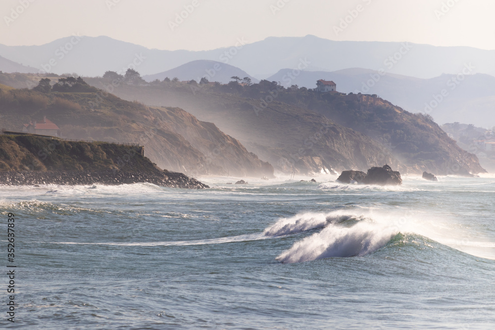Landscape of a rocky shoreline with waves breaking at sunset in a windy day. Horizontal image Landscape of a rocky shoreline with waves breaking at sunset in a windy day. Horizontal image