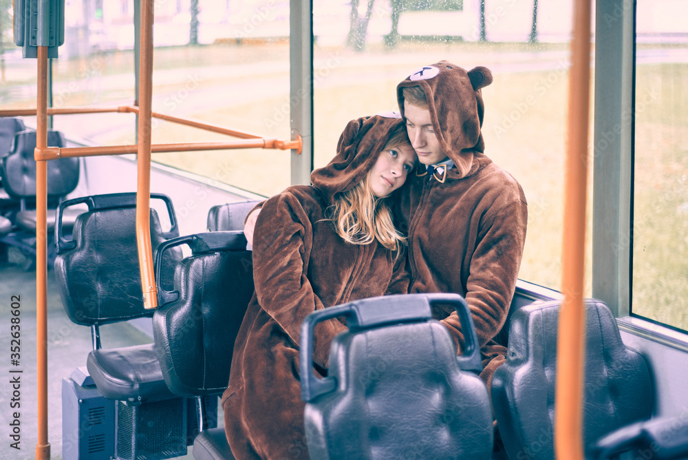 young couple in bear costumes. guy and girl in transport cuddle.