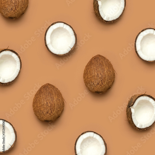 Creative layout with coconuts pattern. Whole and half coconut on brown background. Minimal flat lay style, top view copy space. Food concept. Tropical exotic fruit, summer golden background. Banner