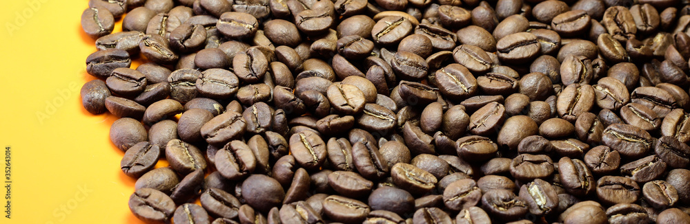 Coffee beans on a bright background. Coffee granules on the yellow table. Texture of coffee beans. Coffee beans on a bright background. Coffee granules on the yellow table. Texture of coffee beans.