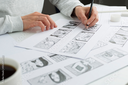 Hands of the artist draw a storyboard on paper. Storytelling. Story frames with heroes.