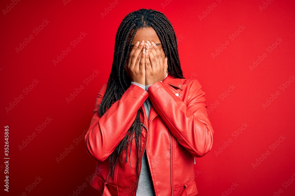 Young african american woman wearing cool fashion leather jacket over red isolated background with sad expression covering face with hands while crying. Depression concept. Young african american woman wearing cool fashion leather jacket over red isolated background with sad expression covering face with hands while crying. Depression concept.