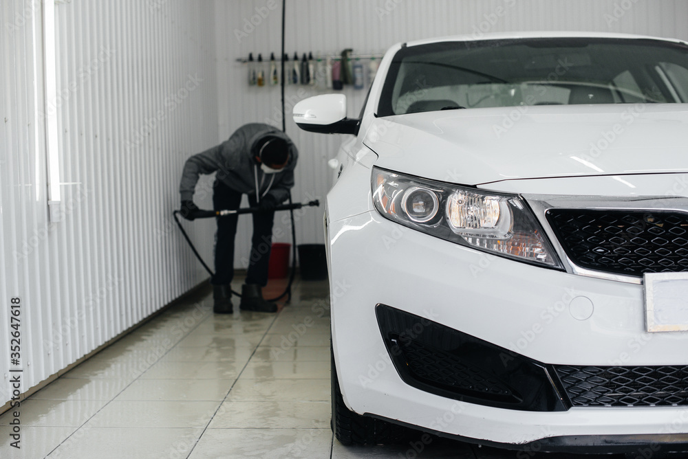 Modern washing with foam and high-pressure water of a white car. Car wash Modern washing with foam and high-pressure water of a white car. Car wash