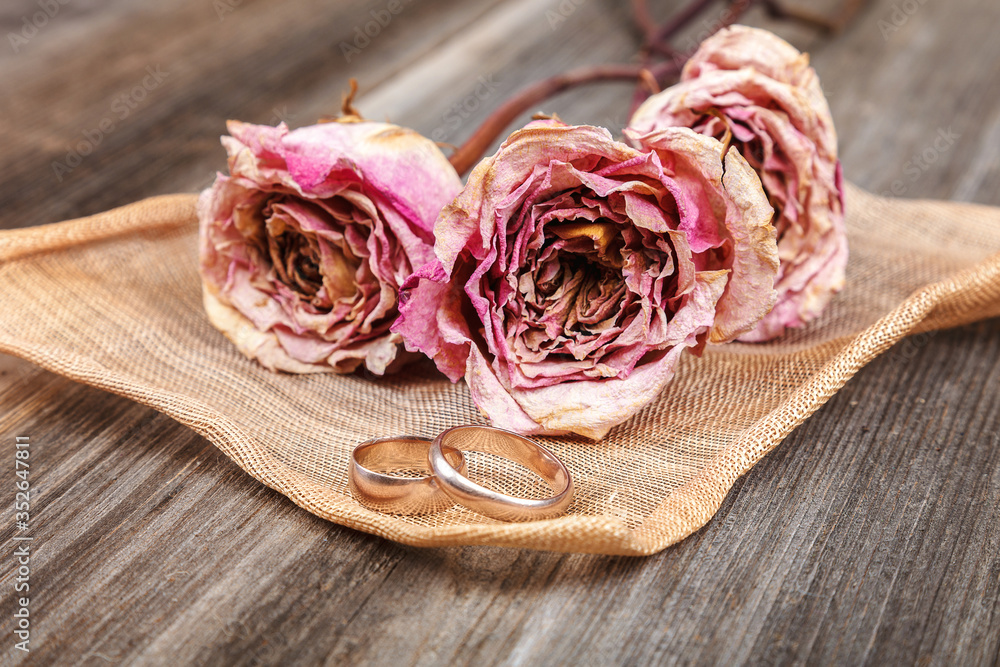 Wedding rings and roses dried flowers on wooden background Wedding rings and roses dried flowers on wooden background