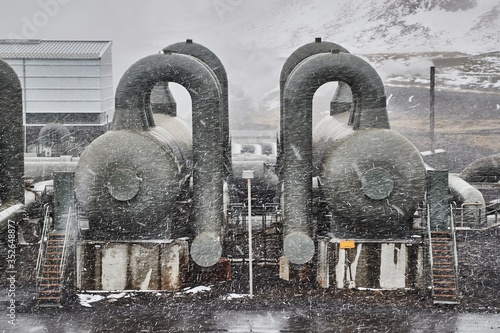 Geothermal power plant in Iceland, pipe stuctures and pressure tanks in heavy snow fall blizzard photo