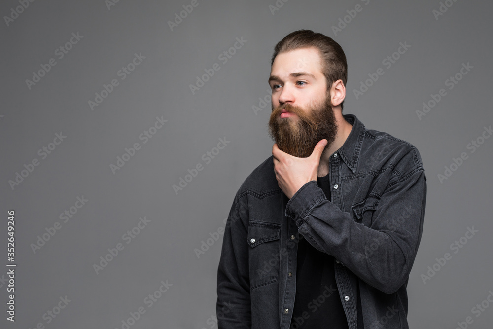 Fototapeta premium Handsome man hipster with long beard moustache and brunette hair in studio on grey background