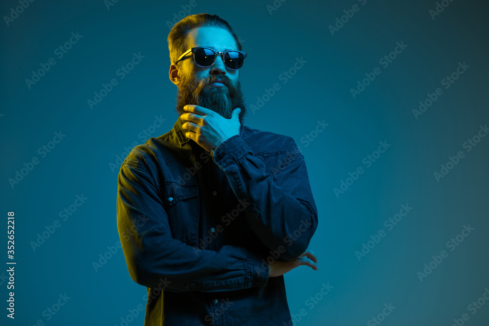 Young hipster man touch beard wearing sunglasses isolated over gray background. Young hipster man touch beard wearing sunglasses isolated over gray background.