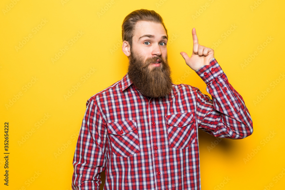Young bearded man pointed up on yellow background Young bearded man pointed up on yellow background
