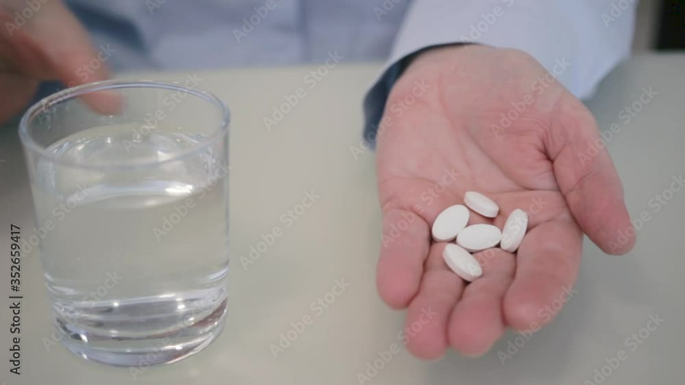 White pills antibiotic treatment, painkiller, or calcium supplements poured into female palm, medicines and health care concept, close-up view White pills antibiotic treatment, painkiller, or calcium supplements poured into female palm, medicines and health care concept, close-up view