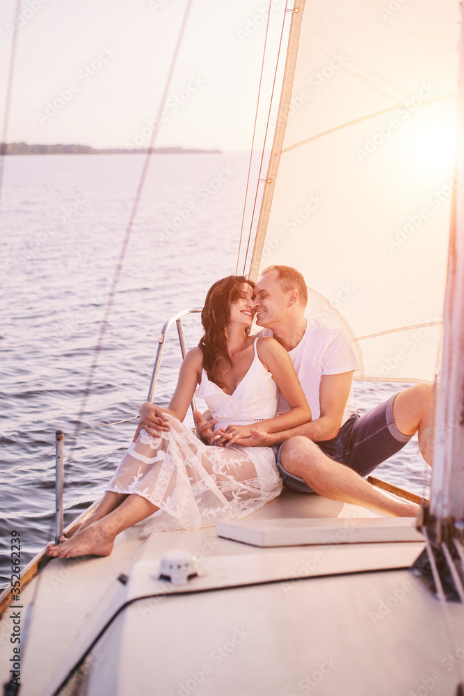 Romantic couple in love on sail boat at sunset under sunlight on yacht - Happy exclusive alternative lifestyle concept - Love story of two caucasian young people.