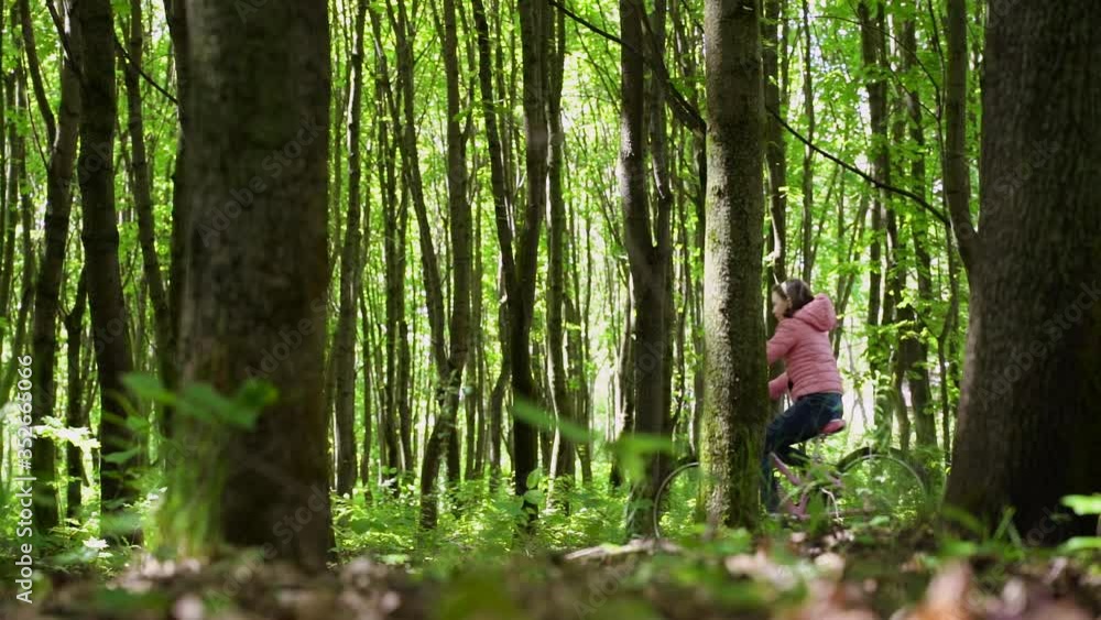Nice girl rides a bicycle on a dirt forest road. The concept of active healthy recreation on nature. Slow motion Nice girl rides a bicycle on a dirt forest road. The concept of active healthy recreation on nature. Slow motion