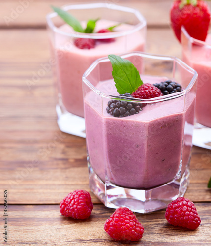 Drink smoothies four summer strawberry, blackberry, kiwi, raspberry on wooden table.