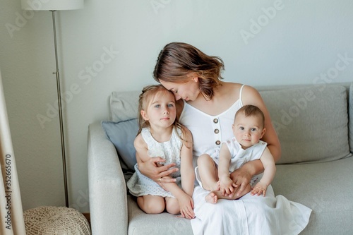 Young beautiful mother Holds her little daughters in her arms. Home comfort. Mothers Day.