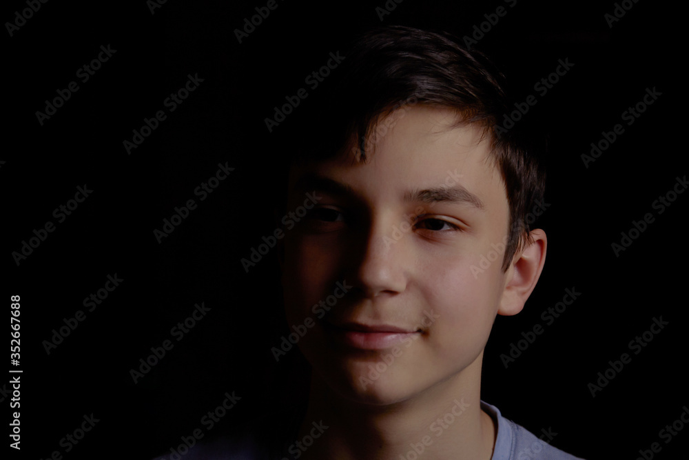 Portrait of a teenager on a black background. The boy has dark hair Portrait of a teenager on a black background. The boy has dark hair