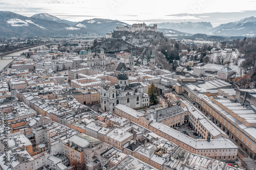 Aerial drone shot view of snowy salzburg city center with view of Cathdrals and fortress in winter photo