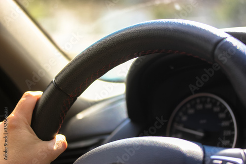The driver holds the steering wheel of the car with his hands while driving: fast ride on the road