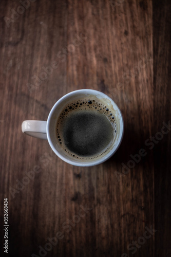 La imagen muestra una taza de caf   en una mesa de madera