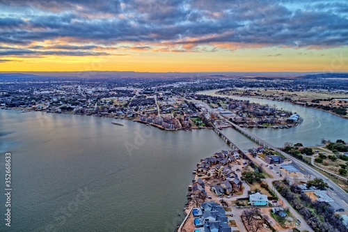 High dynamic range aerial sunset photo of lake, bridge and town under cloudy skies with vivid sunset. Contrasting warm and cool tones.    photo