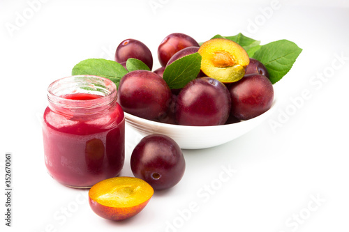 Violet fresh ripe plums and a glass with a puree from plums, background