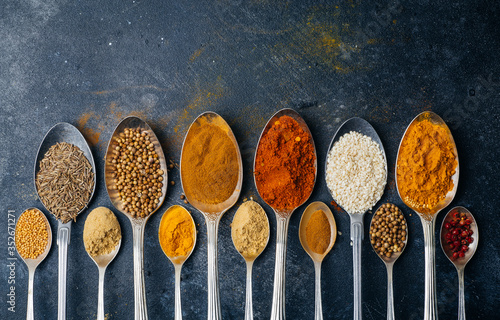 Spices in spoons background. Varieties of spices (turmeric, pepper, chili, coriander, cinnamon) and peppers for cooking. Culinary food concept.