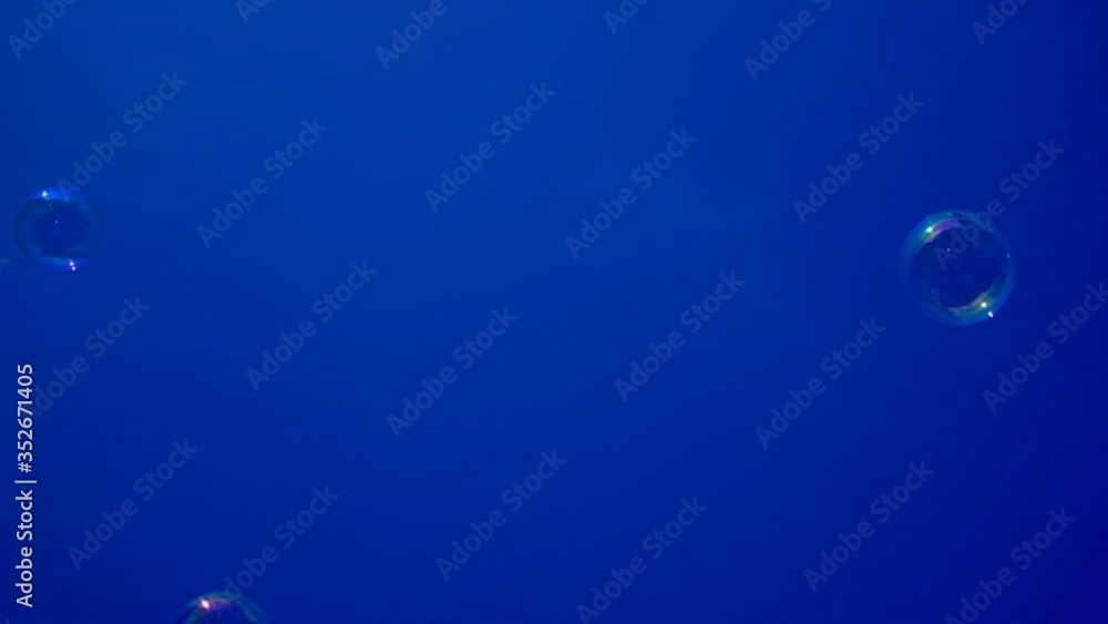 Blurred soap bubbles floating in the cloudless sky in slow motion, selective focus on subject and bottom view shot Blurred soap bubbles floating in the cloudless sky in slow motion, selective focus on subject and bottom view shot