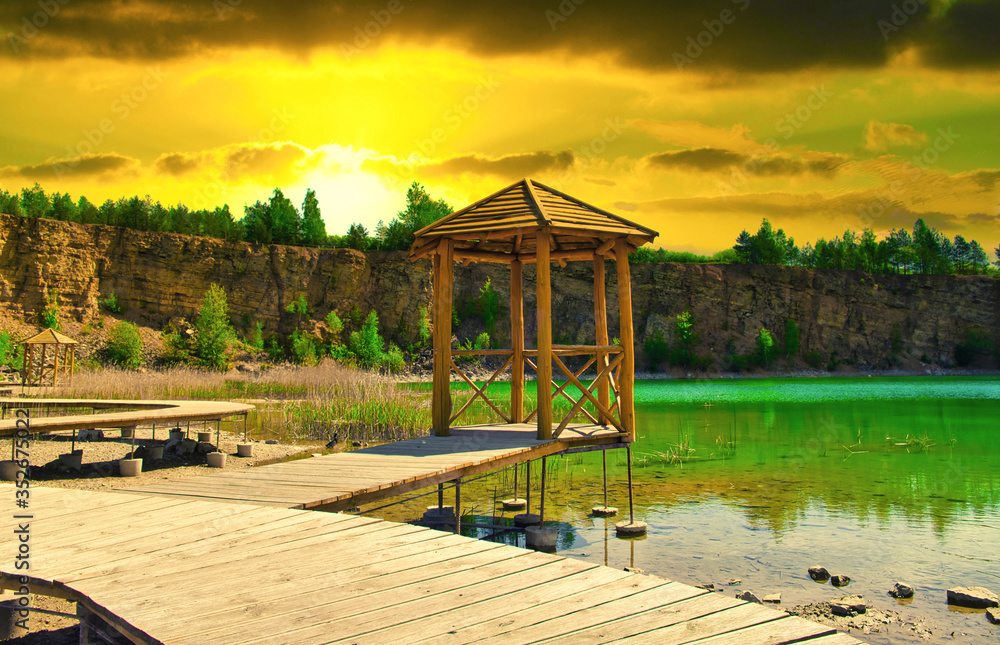 A turquoise lake in the midst of a canyon. Travel and rest concept. A house by the lake, a wooden footbridge going deep into the turquoise lake. A turquoise lake in the midst of a canyon. Travel and rest concept. A house by the lake, a wooden footbridge going deep into the turquoise lake.
