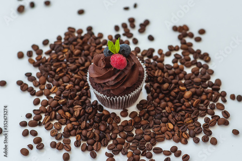 cupcake with currants and raspberries surrounded by coffee beans