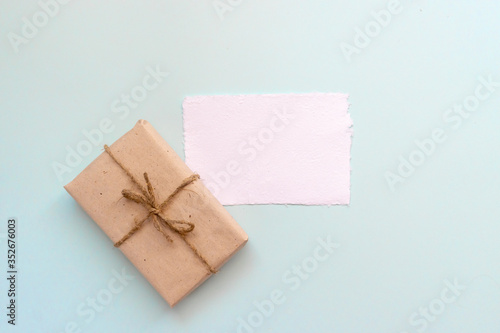 Gift box with kraft paper and a sheet of paper for text on a light blue background. Flat lay for father's day concept.