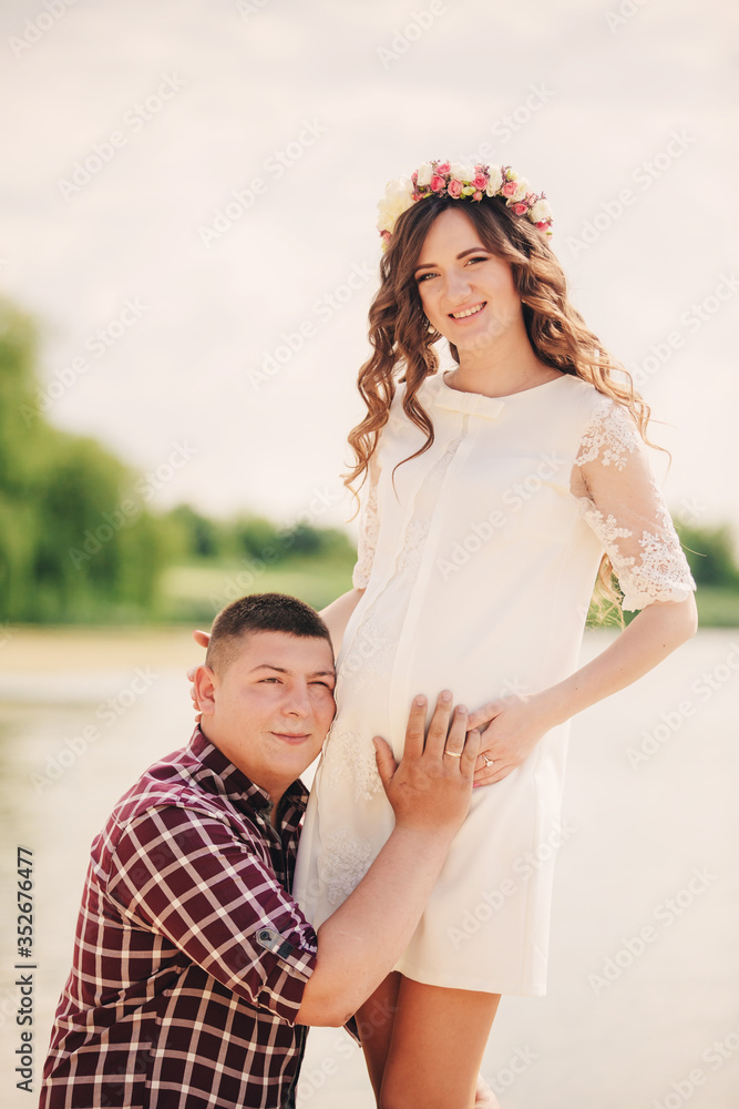 In waiting baby. pregnant woman with beloved husband stand near lake. round belly. Husband kneeling embraces wife a round belly. Parenthood. The sincere tender moments. In waiting baby. pregnant woman with beloved husband stand near lake. round belly. Husband kneeling embraces wife a round belly. Parenthood. The sincere tender moments.