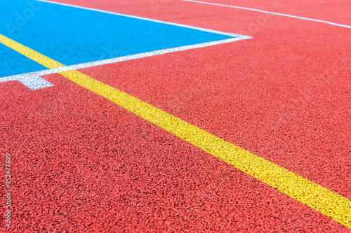 Colorful sports court background. Top view to red and blue field rubber ground with white and yellow lines outdoors © vejaa