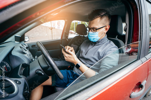 Young taxi driver in medical mask with a smartphone in his hand © andrew_shots