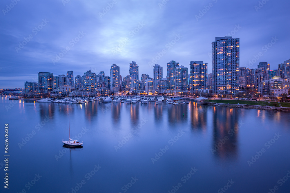Vancouver downtown architecture and boat with water reflections at dusk