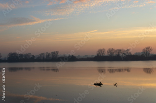 river landscape under a sunrise and clouds reflected in the water