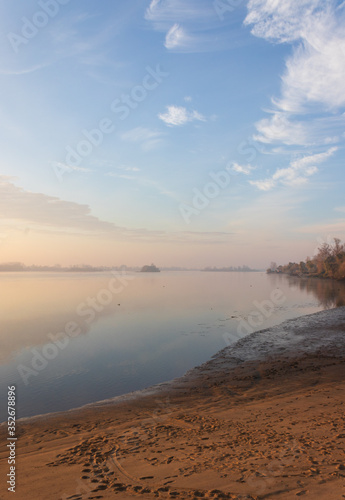 landscape of a river beach at sunrise under a painted cloud sky