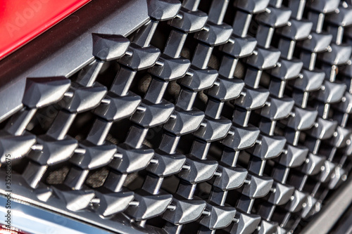 The black radiator grille on the red car. Close-up. Horizontal orientation. 