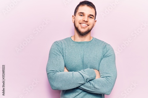 Young handsome man wearing casual sweater happy face smiling with crossed arms looking at the camera. positive person.