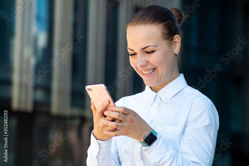 Happy positive cheerful business woman, young beautiful girl looking at smartphone, phone cell mobile telephone, smiling get good news, reading or typing message. Technology, gadget, happiness concept