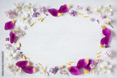Fototapeta Naklejka Na Ścianę i Meble -  Petals of tulips, apple flowers, lilac flowers on a white wooden background. Space for text.