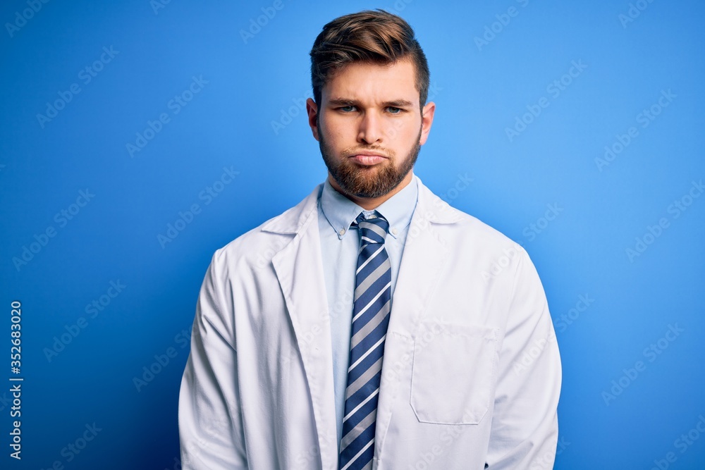 Young blond therapist man with beard and blue eyes wearing coat and tie over background depressed and worry for distress, crying angry and afraid. Sad expression. Young blond therapist man with beard and blue eyes wearing coat and tie over background depressed and worry for distress, crying angry and afraid. Sad expression.