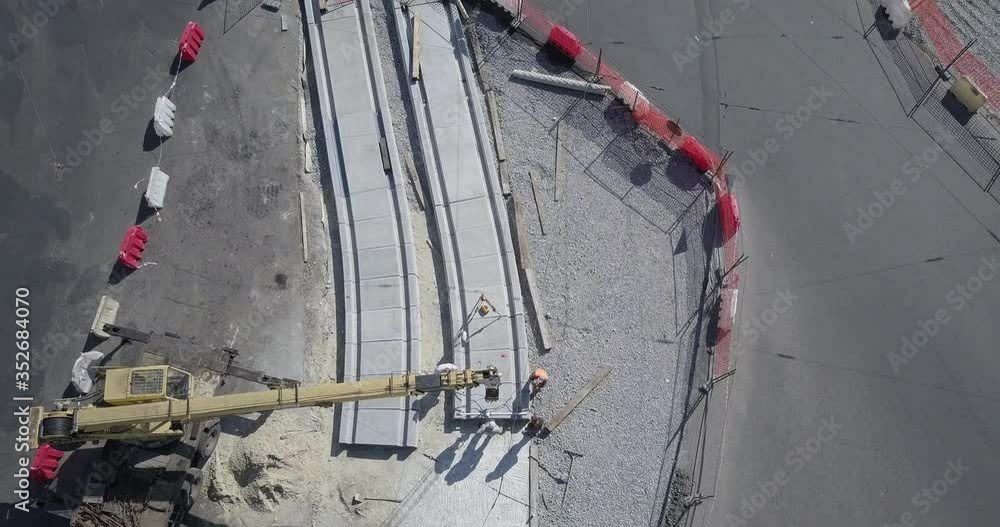 Work machinery on the construction of a road with plate installation by crane. Crushed stone on substrate. Support activities and reconstruction of tram tracks. Aerial view from drone Work machinery on the construction of a road with plate installation by crane. Crushed stone on substrate. Support activities and reconstruction of tram tracks. Aerial view from drone