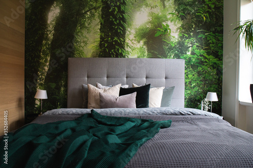 Bed with fluffy cushions in front of a jungle wallpaper photo