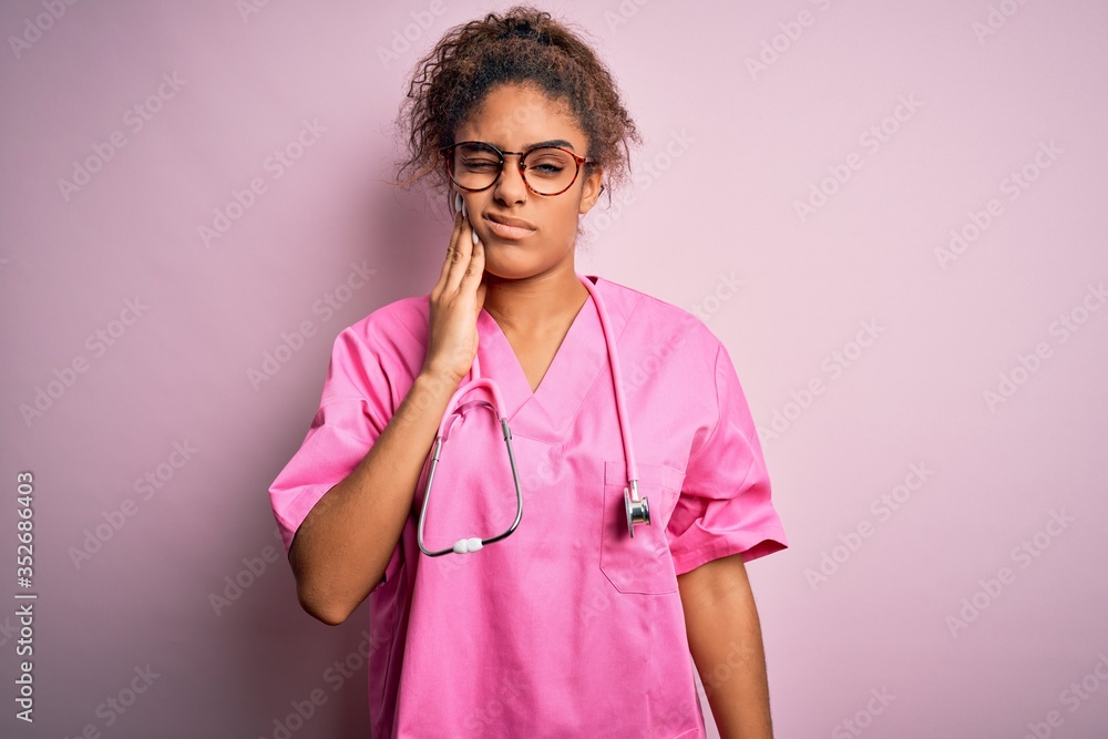 African american nurse girl wearing medical uniform and stethoscope over pink background touching mouth with hand with painful expression because of toothache or dental illness on teeth. Dentist African american nurse girl wearing medical uniform and stethoscope over pink background touching mouth with hand with painful expression because of toothache or dental illness on teeth. Dentist
