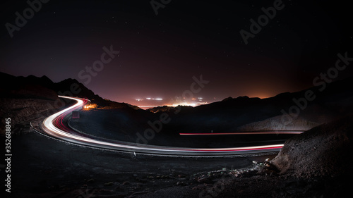 highway long exposure vehicle light trails curvy highway between mountains at starry night 